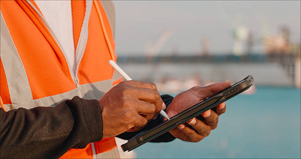 istock Young engineers using digital tablets and note reports plan to repair or rebuild a large bulk ship damaged at a Commercial Shipyard. 2214155960