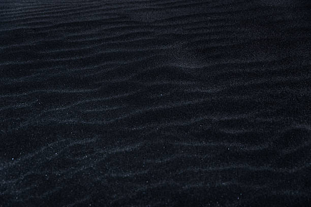 Close-up view of rippling textures on a stretch of fine black volcanic sand, capturing the delicate patterns formed by wind on the beach near Vestrahorn in Iceland.