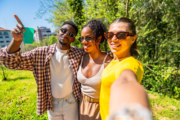 istock Young friends taking a selfie in the park and pointing at something 2214177302