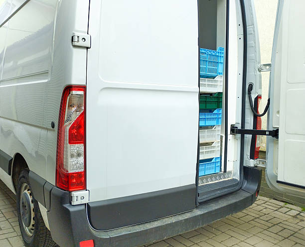 istock The rear of a white van with open doors is partially loaded with blue, white, and green plastic crates. The van is parked on paving stones. 2214181417