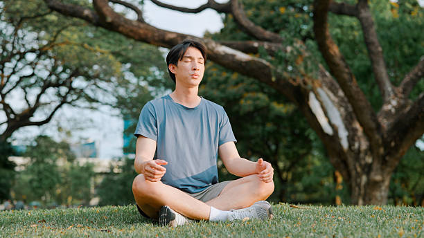 istock Asian man doing meditating in public park 2214182379