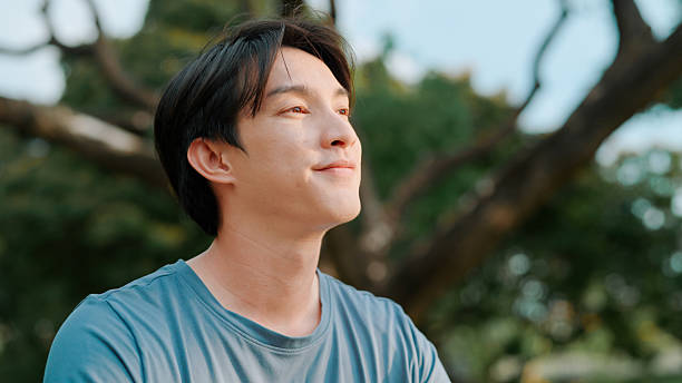 istock Asian man looking away in public park 2214182545