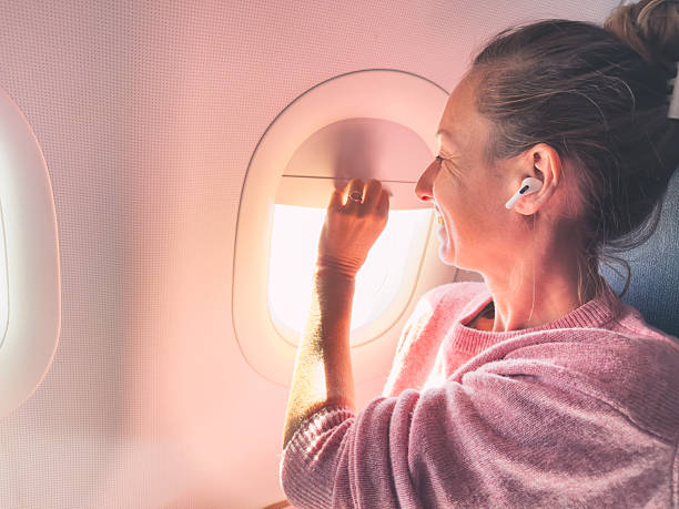 istock Woman Adjusting Airplane Window Shade While Smiling 2214182582