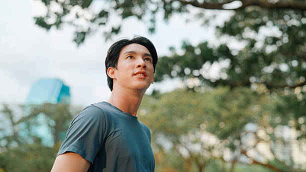 istock Asian man looking away in public park 2214182669
