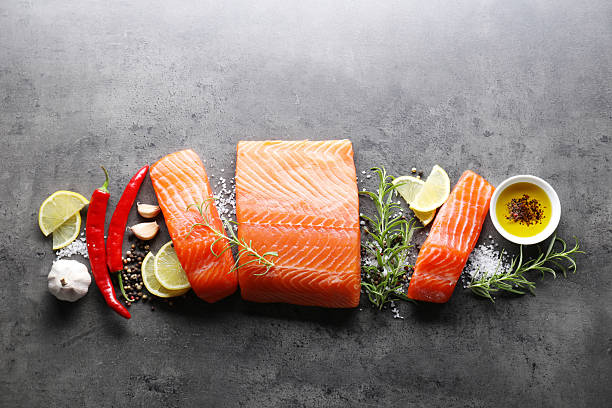 istock Pieces of fresh salmon, lemon and spices on grey table, flat lay 2214182841