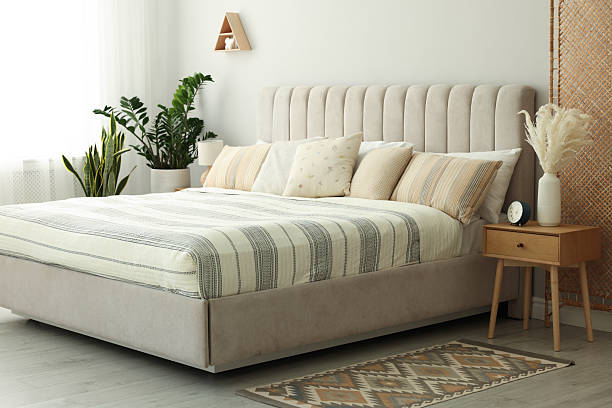 istock Large bed, houseplants and bedside table in stylish room 2214183247