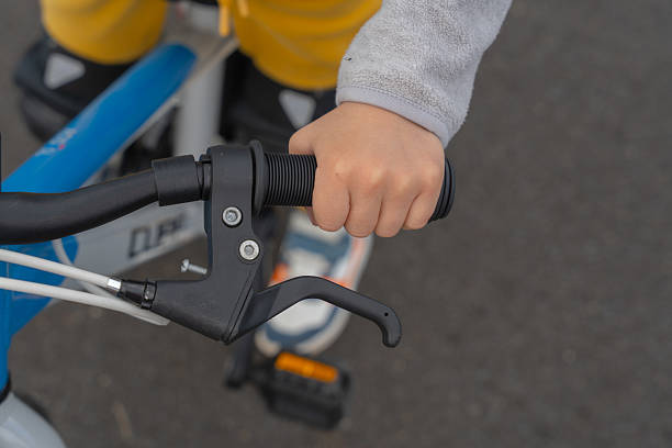 Close-up of a child's hand gripping a bicycle handlebar, showing the learning process and focus. The image highlights a key moment in a child's development