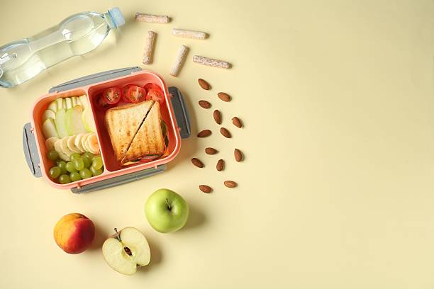 istock Lunch box with snacks and bottle of water on yellow table, flat lay. Space for text 2214185815
