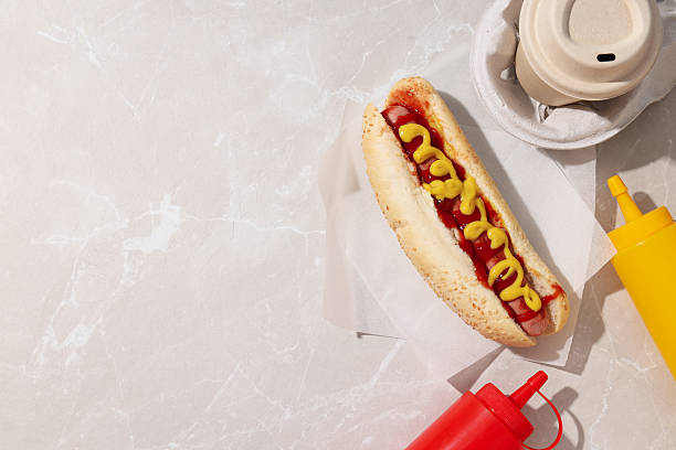 istock Hot dog, sauces in bottles and paper cup on light background, space for text 2214186236