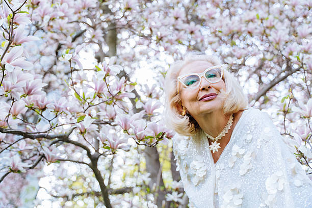 istock Elderly woman Looking through blossoms 2214186606