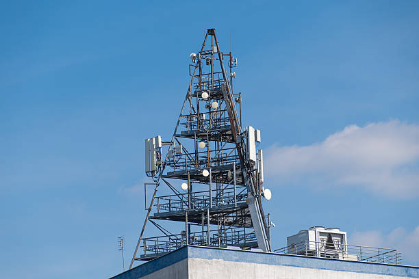 istock Cell tower on building rooftop with antennas against blue sky 2214186857