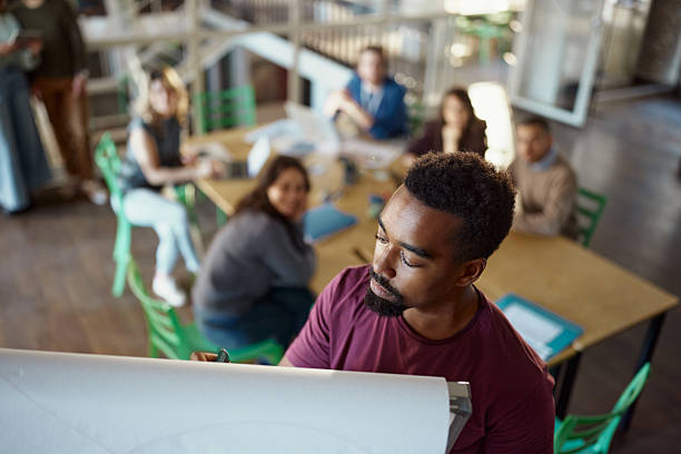 istock Black male leader writing plans on whiteboard during presentation in the office. 2214188804