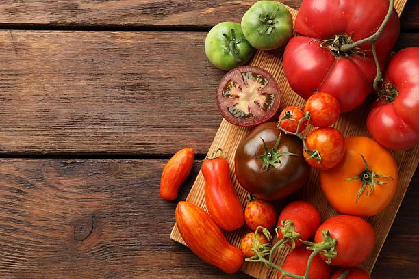 istock Different ripe tomatoes on wooden table, top view. Space for text 2214190158