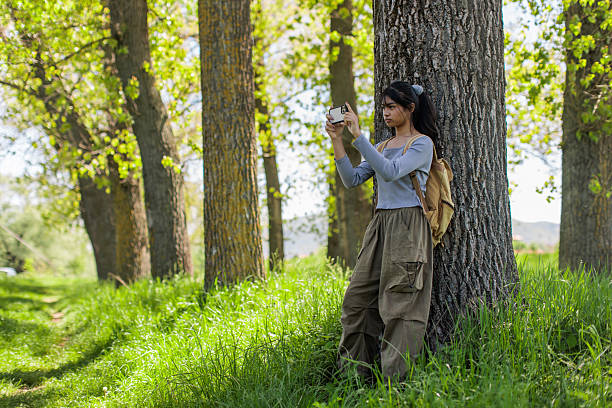 A teenage Filipino girl using her smartphone while on a hike in a wooded area