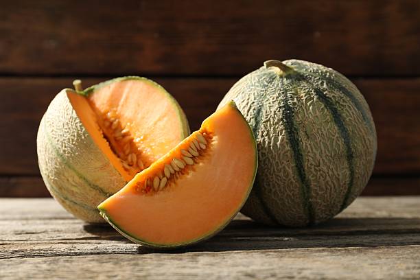 istock Whole and cut ripe Cantaloupe melons on wooden table 2214190499