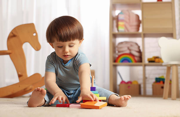 istock Cute little boy playing with toy pyramid on floor at home, space for text 2214191107