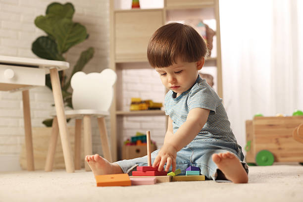 istock Cute little boy playing with toy pyramid on floor at home, space for text 2214191113