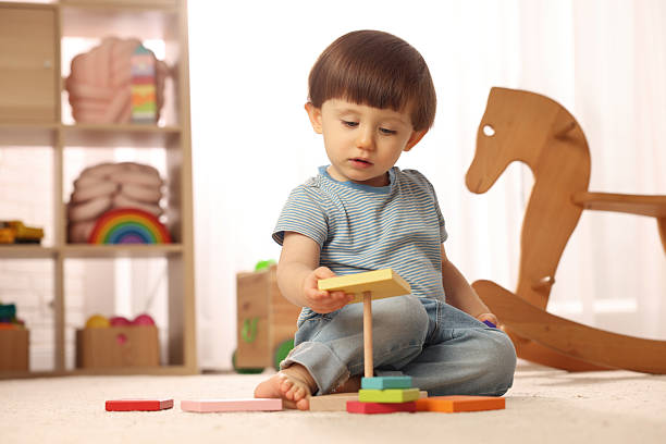 istock Cute little boy playing with toy pyramid on floor at home, space for text 2214191116