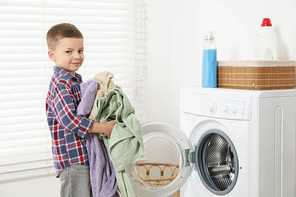 istock Little helper. Cute boy doing laundry at home 2214191662