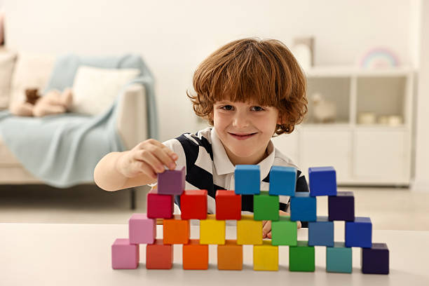 istock Little boy stacking colorful cubes at white table indoors 2214192295