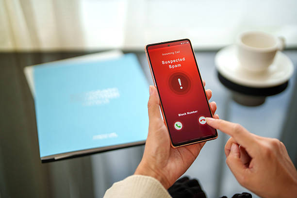Suspected Spam Call Notification on Smartphone A user interacting with a smartphone screen displaying an incoming call marked as "Suspected Spam." The interface includes options to answer, block, or decline the call, representing security awareness. suspicious message stock pictures, royalty-free photos & images