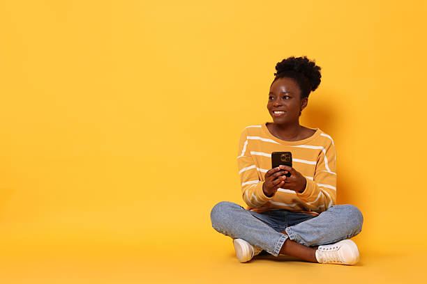 istock Happy woman with smartphone on yellow background. Space for text 2214192474