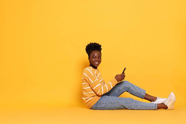 istock Happy woman with smartphone on yellow background. Space for text 2214192481