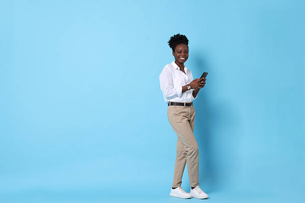 istock Happy woman with smartphone on light blue background. Space for text 2214192571