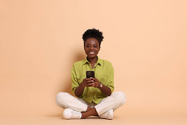 istock Happy woman with smartphone on beige background. Space for text 2214192597