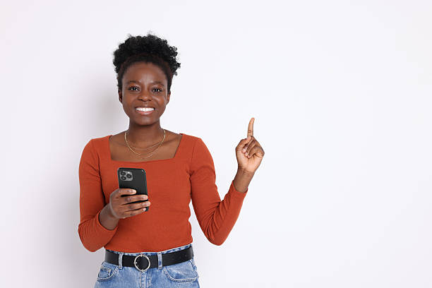 istock Cheerful woman with smartphone pointing at something on white background. Space for text 2214192624