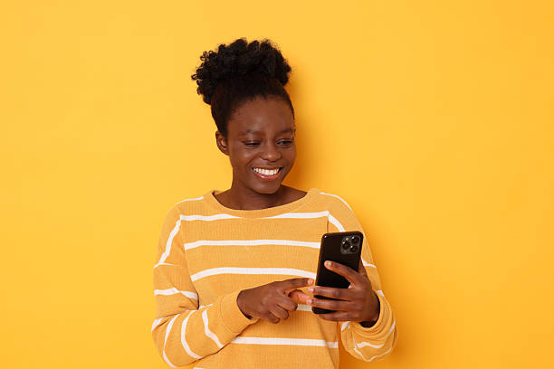 istock Happy woman with smartphone on yellow background 2214192683