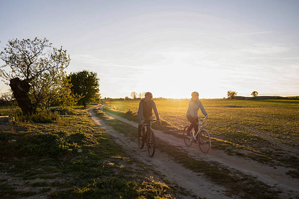 istock Couple riding bicycles on country road at sunset 2214199949