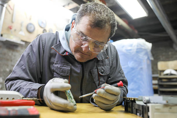 Senior computer technician (50+) performing computer maintenance. Concept: disassembly, cleaning, repair, and restoring the computer to full working condition