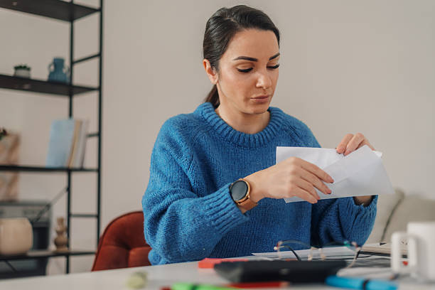 istock Woman opening envelope and reading documents at home office desk 2214202847