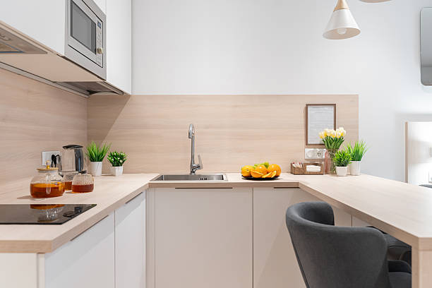 istock a small, bright kitchen with wooden countertops. built-in kitchen with lower and upper cabinets. There is a teapot and mugs of tea on the countertop, flowers in a vase, fruits on a plate. 2214207377