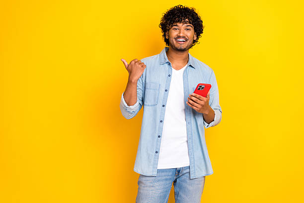 istock Photo of good mood cute guy dressed denim jacket texting modern gadget thumb empty space isolated yellow color background 2214209067