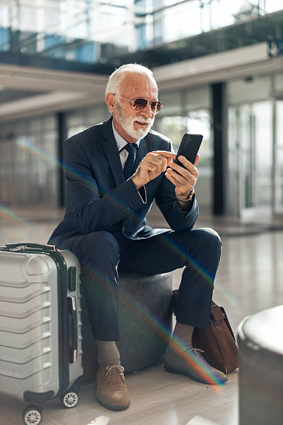 istock Senior Businessman Using Mobile Phone in Modern Airport Terminal 2214210483