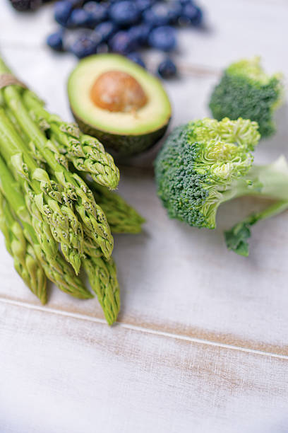 Asparagus, broccoli and avocado on white wooden table