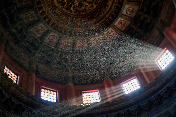 Light beams shine through a grand cathedral dome, revealing intricate Baroque frescoes, windows, and sacred religious architectural details.