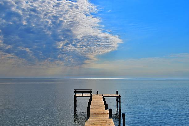 Chesapeake Bay fishing pier, calm water, and a blue sky with an altocumulus cloud in Springtime, southern Maryland