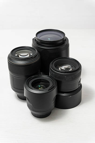 istock Group of four black camera lenses on white surface. 2214221002
