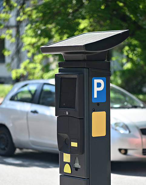 istock Solar-powered parking meter stands next to a parked car, showcasing modern urban infrastructure in daylight 2214226988
