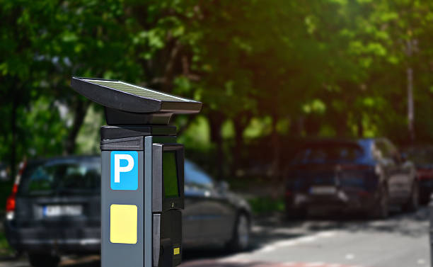 istock A modern parking meter is visible on a sunny day, surrounded by parked cars along a tree-lined street in an urban setting 2214227020