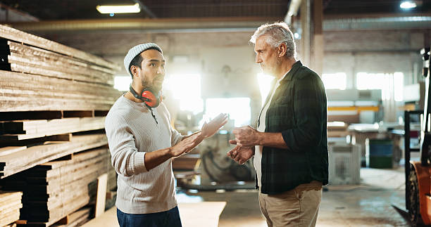 istock Collaboration, planning and talking with carpenter men in workshop for manufacturing or production. Carpentry, industry and teamwork with woodworking people in factory together for conversation 2214229011