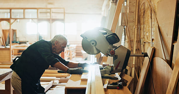 istock Workshop, man and machine with plank for carpenter, diy manufacturing and production business. Warehouse, mature person and contractor with saw tools for professional service, maintenance or cut wood 2214229028