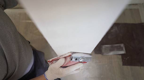 istock Concrete wall background, hand plastering with plastic sponge to finish cement wall. A worker manually polishes a white wall with a sanding sponge. Young adult man polishing a white wall with a sanding sponge by hand. Empty space for text. 2214231134