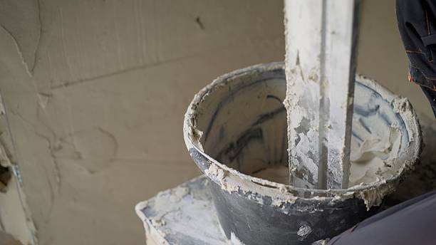 istock Construction worker mixing plaster in bucket with mixing paddle 2214231220