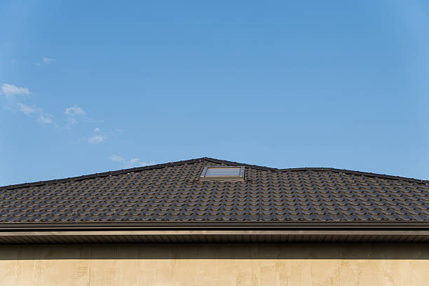 istock A black-tiled roof features a skylight, set against a clear blue sky, showcasing the architectural details of a suburban home 2214233931