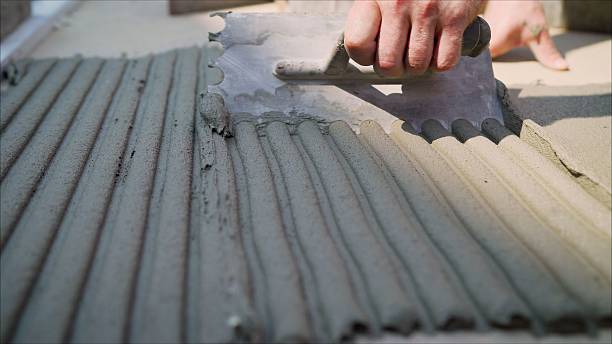 istock Hands perform cement work, apply cement to the surface. Laying stone on a walking path. The glue solution is leveled using a spatula. Applying mortar when laying paving stones. 2214234524