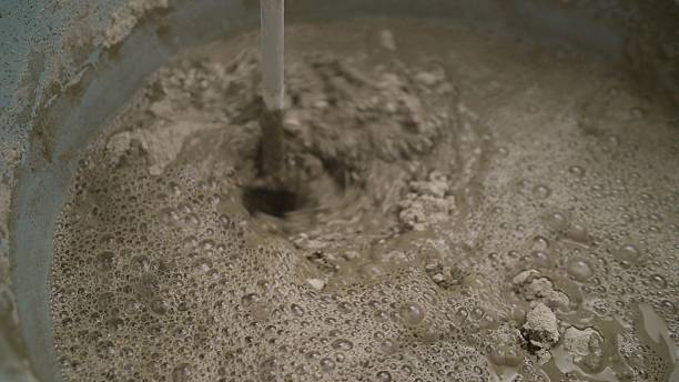 istock Construction worker pouring water into cement mix for building project 2214235130
